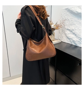 Brown vintage hobo tote bag shown on shoulder in a minimalist interior setting