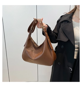 Detail of brown leather hobo shoulder bag with wide strap and golden eyelet buckle