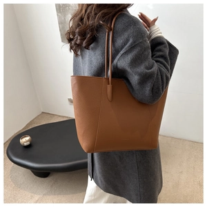 Grand sac cabas en cuir grainé marron porté à l'épaule par un mannequin pour le style