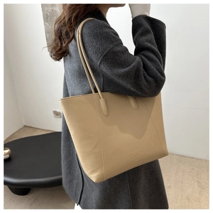 Close-up of beige lychee grain leather tote bag featuring a minimalist shoulder strap design