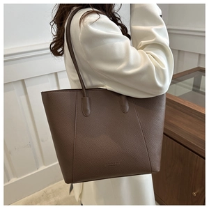 Detail of large brown pebble leather tote bag with embossed fashion text and slim straps
