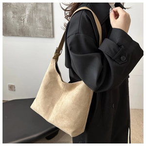 Detail of adjustable dark brown leather strap on a beige matte suede hobo shoulder bag
