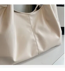 Detailed close-up showing the soft PU leather texture and vertical stitching on the beige tote