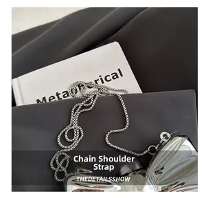 Detail of silver mirror butterfly bag with metallic chain strap on textured fabric
