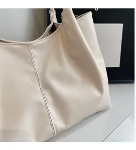 Close-up of cream white tote bag showing soft faux leather texture and vertical stitching