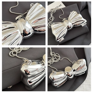 Detail view of mirror finish silver bow clutch bag with detachable ball chain strap