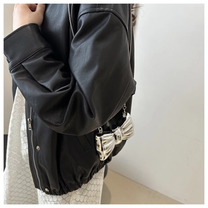 Silver bow-shaped acrylic crossbody bag with chain strap shown on model in leather jacket