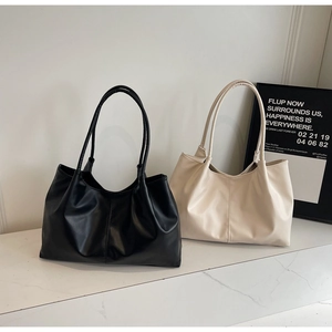 Minimalist leather tote bags in black and beige displayed on a white stone surface