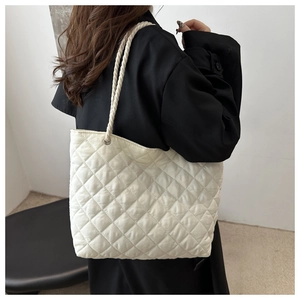 Sac cabas en nylon matelassé blanc crème avec anses en corde sur l'épaule du modèle