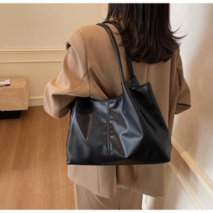 Detail of minimalist black faux leather tote bag with vertical stitching and slim handles