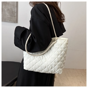 Détail du sac cabas matelassé blanc avec anses en corde épaisse sur un modèle