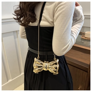 Detailed back view of a golden bow-shaped metallic evening clutch with a fine chain strap