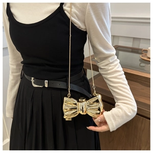 Detailed close-up of a golden metal bow-shaped mini chain bag with metallic finish