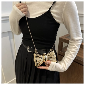 Close-up of golden bow-shaped acrylic crossbody bag with a shiny metallic mirror finish