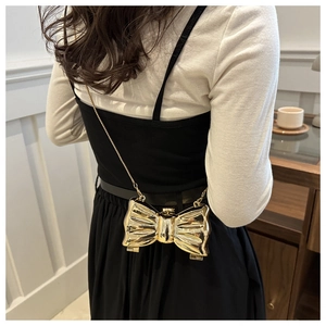Detail of champagne gold bow-shaped acrylic crossbody bag with a metal chain strap