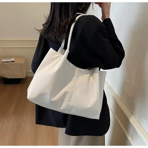 Minimalist white tote bag detail showing vertical stitching and smooth leather texture