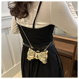 Detailed view of a gold bow-shaped mini acrylic clutch with a delicate metal chain strap