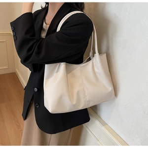 Detail view of cream tote bag with vertical stitching on model in minimalist setting