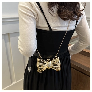 Golden bow-shaped mini metal clutch with textured metallic finish and chain strap