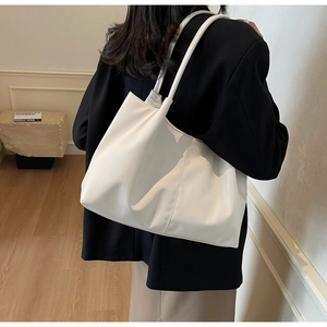 Minimalist white tote bag detail showing matte finish leather texture and shoulder strap