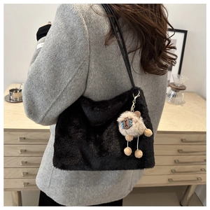 Detail of a black plush shoulder bag with a cute brown sheep charm for autumn and winter