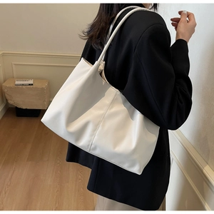 Detailed side view of a white soft faux leather tote bag worn on a person shoulder