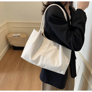 White pleated PU leather tote bag with slim shoulder strap shown on a model's shoulder