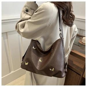 Detail of dark brown leather tote bag with butterfly gold ornaments on model