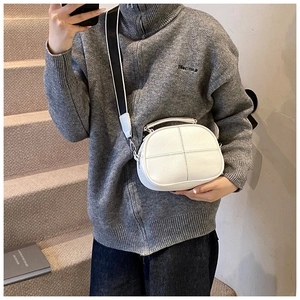 Close-up of white pebble grain cross-body pillow bag with wide strap on a model