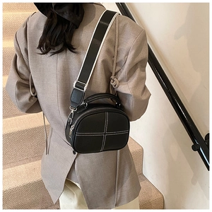 Detail of black pebbled leather crossbody bag featuring white cross-stitch and top handle