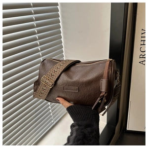 Detailansicht der dunkelbraunen Zylindertasche aus Leder mit gewebtem Ethno-Schultergurt