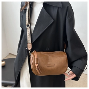 Detail of brown leather Boston bag with houndstooth strap and fashion logo plaque