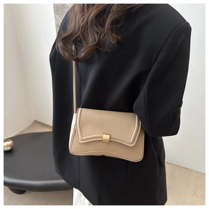 Close-up of beige square handbag with gold metal clasp on a black blazer background