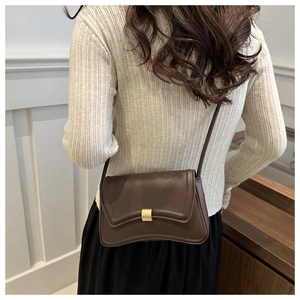 Detail view of a dark brown crescent-shaped crossbody bag with gold metal buckle decoration