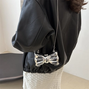 Chic silver bow-shaped metallic mini bag with chain strap shown on a leather jacket