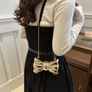 Elegant gold bow-shaped acrylic mini crossbody bag with sleek metallic chain strap