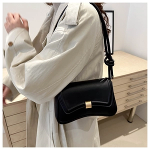 Elegant black square bag with curved bottom and golden buckle shown on a model