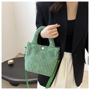 Detail of green corduroy bucket bag with ring handle and detachable shoulder strap