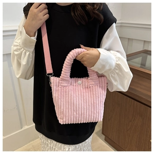 Detail of pink corduroy bucket bag showing textured fabric and silver metal clasp