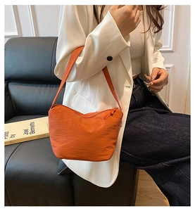 Détail de la texture plissée du sac à bandoulière en nylon orange et sa forme seau