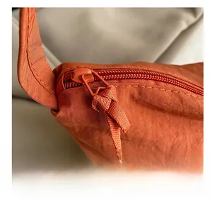 Détail macro de la fermeture éclair en résine et texture plissée sur le sac orange