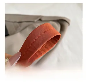 Gros plan sur la bandoulière orange avec double couture renforcée et texture tissée du sac