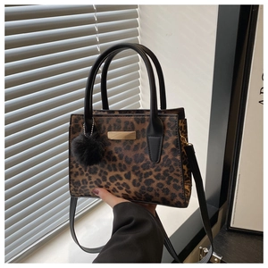 Détail du sac léopard avec pompon en fourrure noire et plaque métallique dorée de luxe