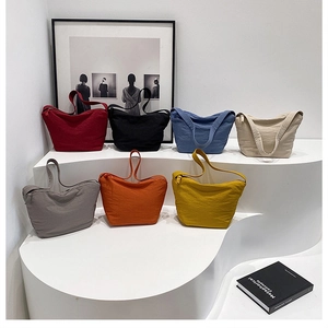 Groupe de sept sacs cabas plissés colorés présentés sur un support à paliers minimaliste