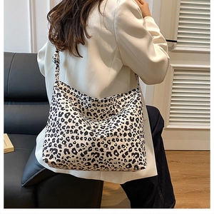 Detail of a large leopard print tote bag with stylish tied shoulder strap on a model