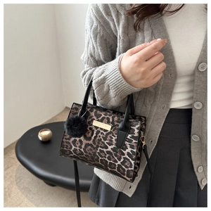 Sac léopard avec plaque métallique dorée et détail de breloque pompon en peluche