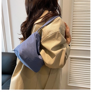 Sac à bandoulière bleu plissé en tissu doux assorti à un trench-coat beige élégant