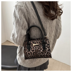 Gros plan sur le sac à bandoulière léopard avec détails dorés et poignée noire
