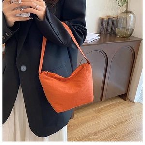 Détail du sac croissant plissé orange montrant la texture nylon et la fermeture éclair