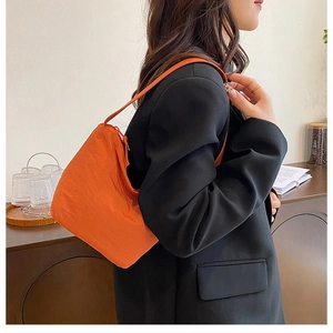 Détail du sac à bandoulière plissé orange vif avec tissu texturé et fine bandoulière